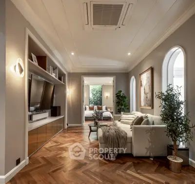 Luxurious living room with elegant decor and herringbone wood flooring, leading to a cozy bedroom.