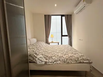 Cozy bedroom with modern decor and natural light from large window.