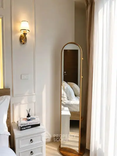 Elegant bedroom with stylish decor, featuring a floor mirror, bedside table, and soft lighting for a cozy ambiance.