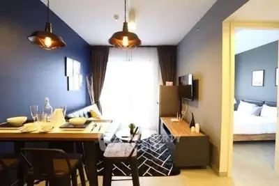 Modern open-plan living room with stylish dining area and cozy bedroom view.