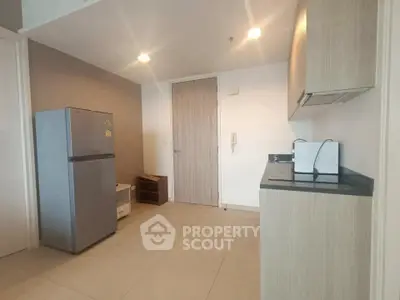 Modern kitchen with sleek cabinets and stainless steel fridge in a minimalist apartment.