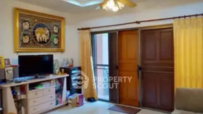 Cozy living room with TV, wooden doors, and elegant decor in a welcoming home.
