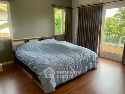 Spacious bedroom with large windows and garden view, featuring a cozy bed and elegant curtains.