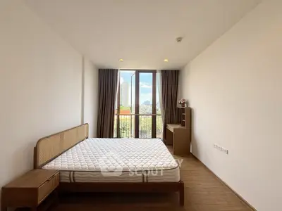 Spacious bedroom with large window and city view, featuring modern furniture and natural light.