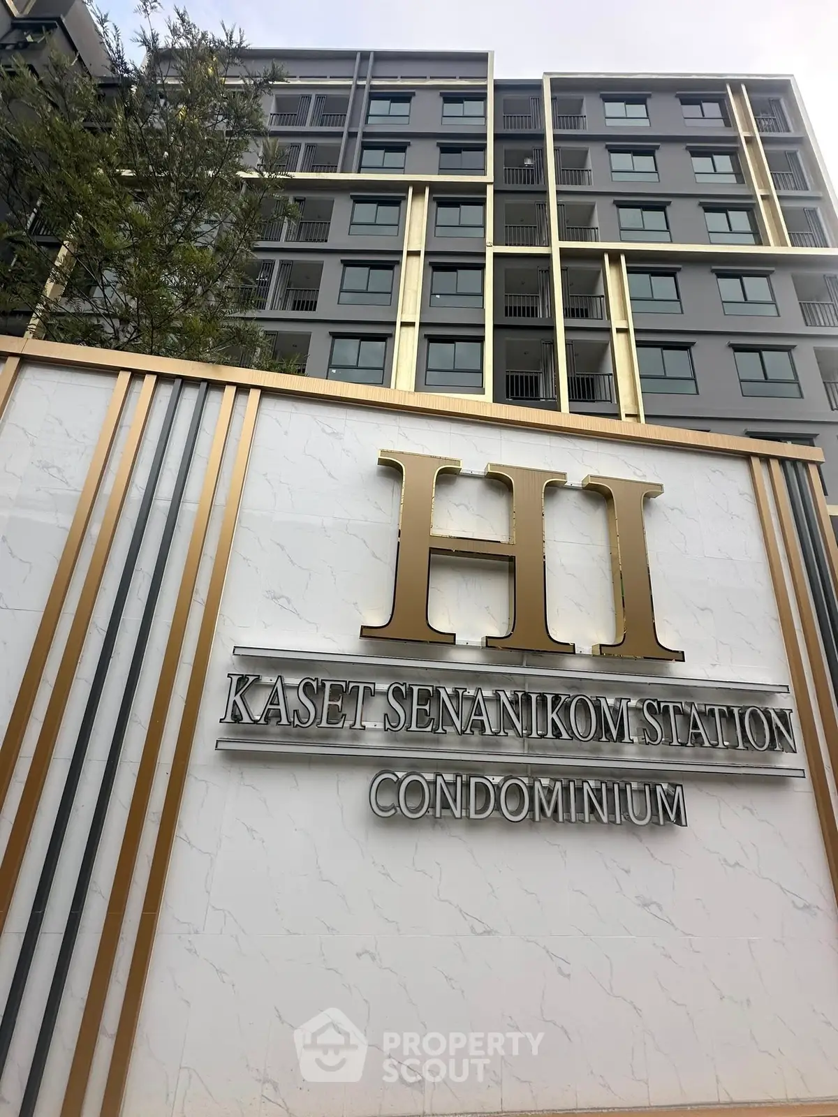 Modern condominium building with elegant signage at Kaset Senanikom Station.