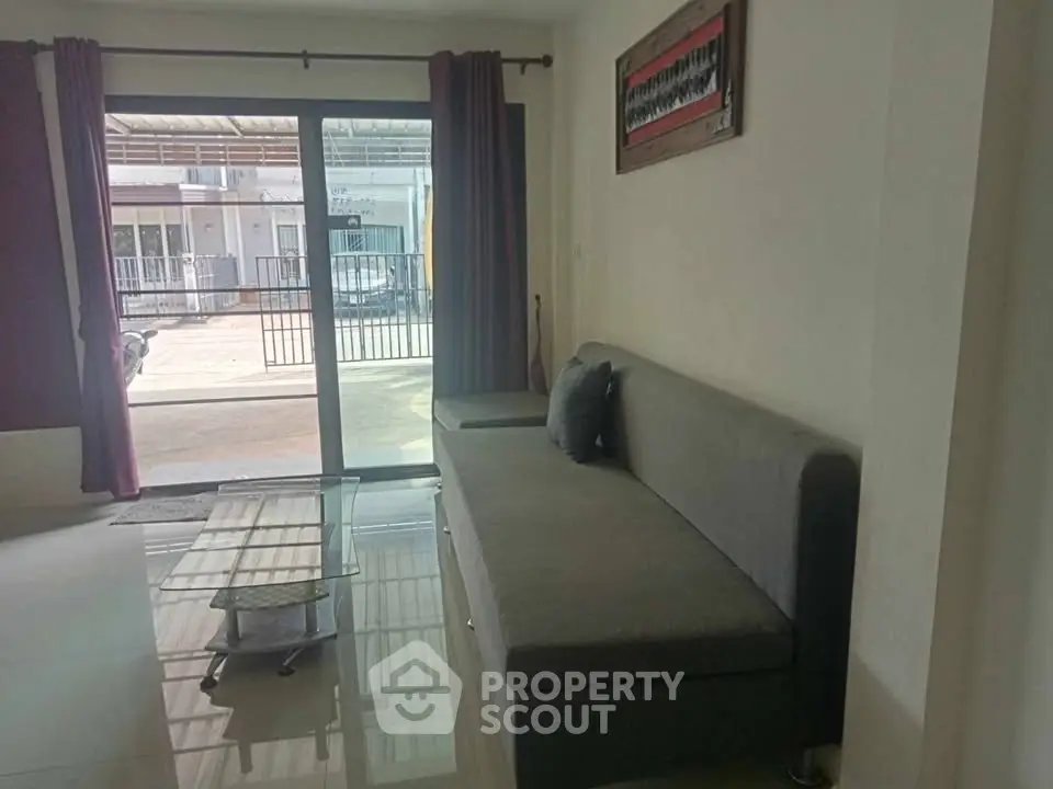 Modern living room with sleek gray sofa and glass coffee table near large sliding doors.