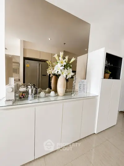 Modern kitchen with sleek cabinetry and elegant decor, featuring a large mirror and stainless steel appliances.