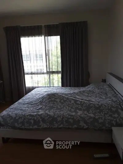 Cozy bedroom with large window and elegant curtains, perfect for relaxation.