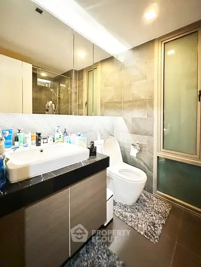 Modern bathroom with sleek fixtures and large mirror in a stylish home.