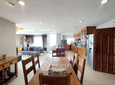 Spacious open-plan living room and kitchen with modern wooden furniture and ample natural light.