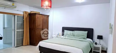 Spacious bedroom with modern decor and ample natural light, featuring a cozy bed and elegant wooden wardrobe.