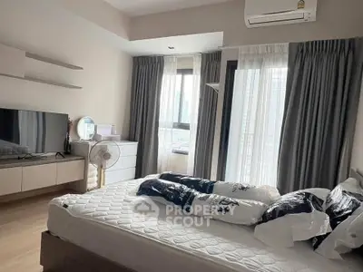 Modern bedroom with city view, featuring sleek furniture and ample natural light.