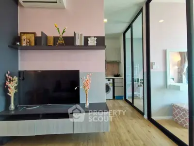Modern living room with TV, stylish shelves, and view into kitchen and bedroom