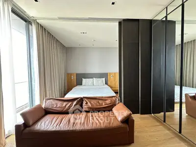 Luxurious bedroom with modern design, featuring a leather sofa and mirrored wardrobe for a stylish touch.