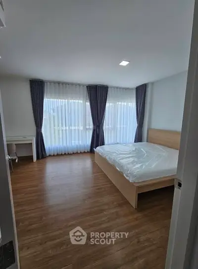 Spacious bedroom with large windows and wooden flooring