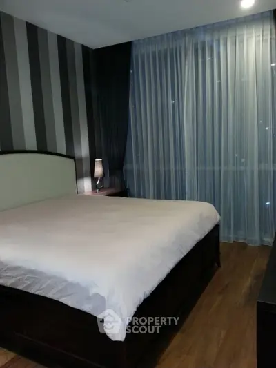 Modern bedroom with striped accent wall and floor-to-ceiling curtains