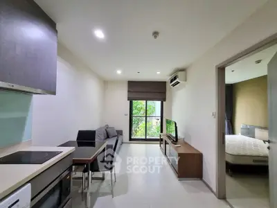 Modern apartment interior with open kitchen and cozy living room, featuring sleek furniture and natural light.