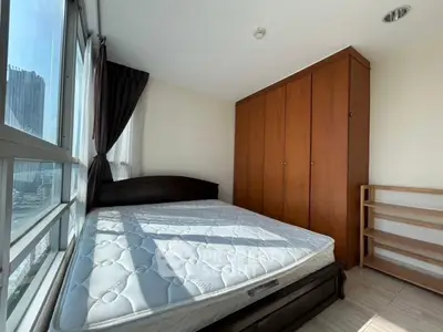 Spacious bedroom with large window and wooden wardrobe in modern apartment