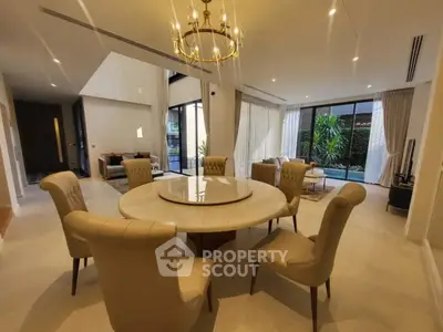 Luxurious open-plan living room with elegant dining area and pool view, featuring modern decor and natural light.