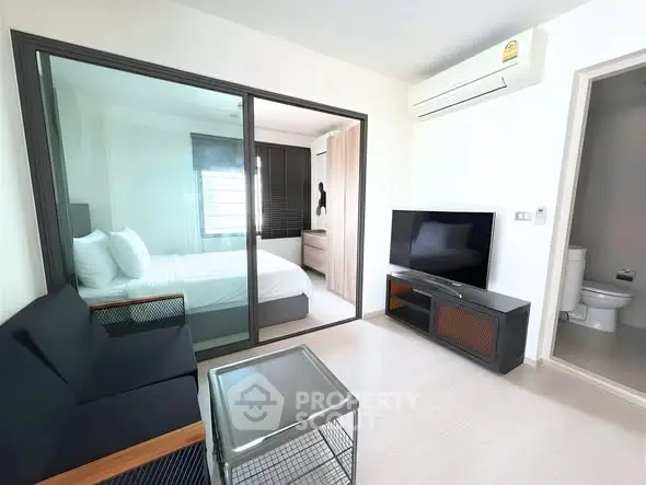 Modern apartment living room with sleek furniture and view into cozy bedroom