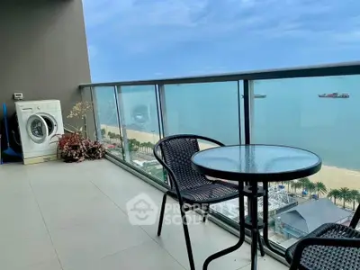 Stunning balcony with ocean view, glass railing, and cozy seating area, perfect for relaxation.
