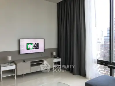 Modern living room with sleek furniture and large window offering city views.