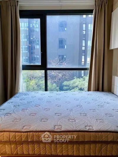 Spacious bedroom with large window offering city view and natural light.