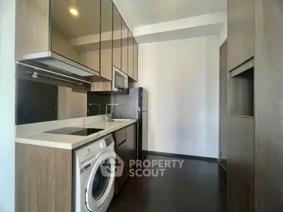 Modern kitchen with sleek cabinetry, washing machine, and built-in appliances in a compact layout.