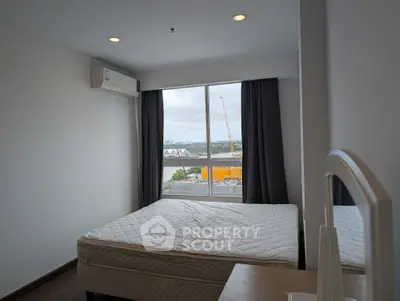 Modern bedroom with large window offering city view, featuring a comfortable bed and air conditioning.