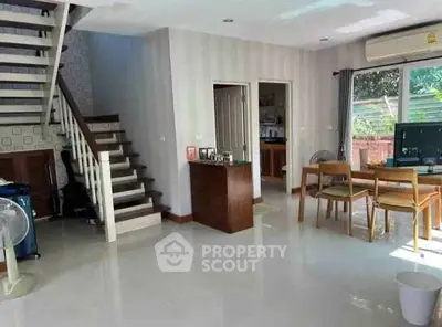 Spacious living room with modern staircase and dining area, featuring natural light and garden view.