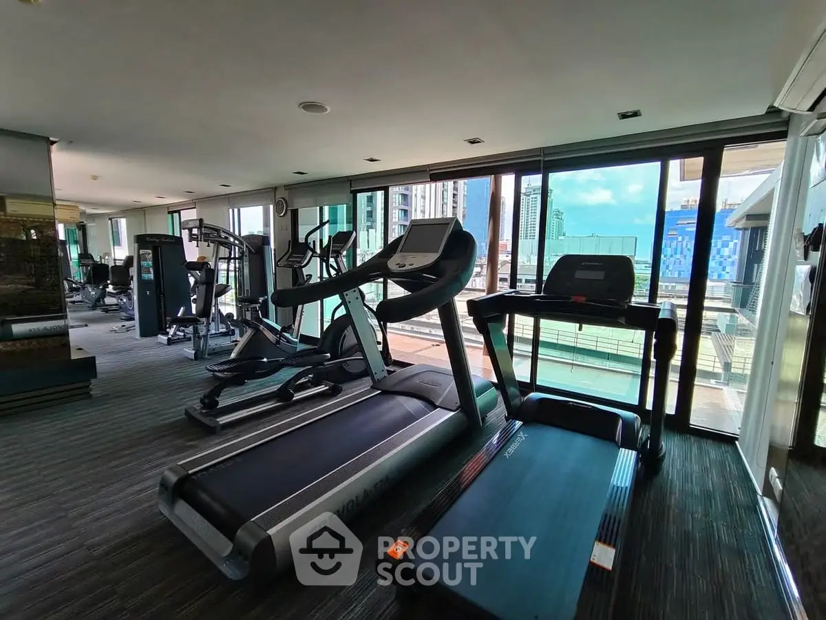 Modern gym with city view featuring state-of-the-art exercise equipment and floor-to-ceiling windows.