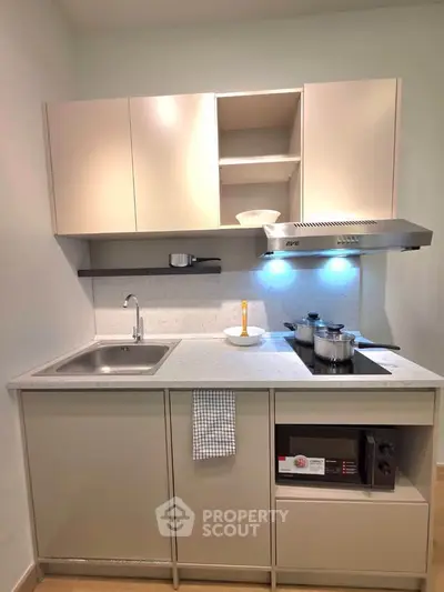Modern compact kitchen with sleek cabinetry and integrated appliances in a stylish apartment.