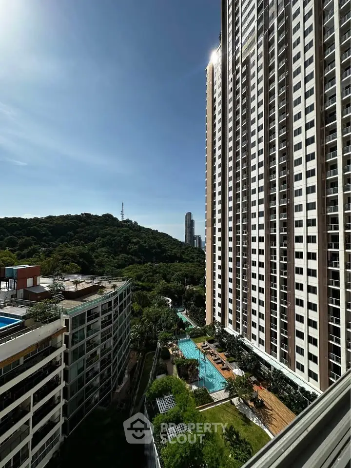 Stunning high-rise apartment view with lush greenery and pool, perfect for urban living.