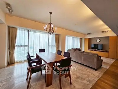 Spacious open-plan living and dining area with elegant chandelier and large windows.