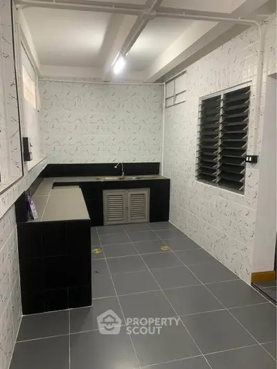 Spacious kitchen with modern black and white tile design, featuring ample counter space and sleek fixtures.