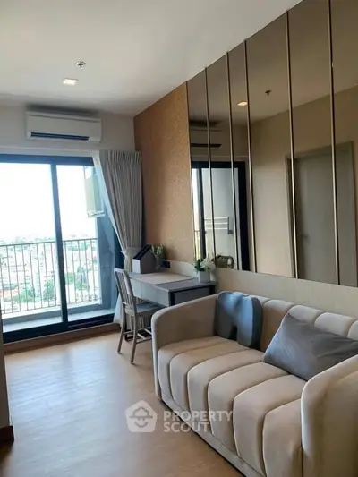 Modern living room with balcony view, featuring stylish sofa and workspace in a high-rise apartment.