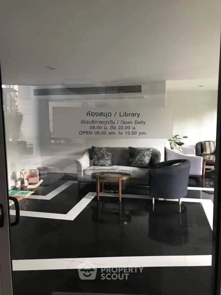 Modern library with stylish seating and sleek black flooring in a real estate property.