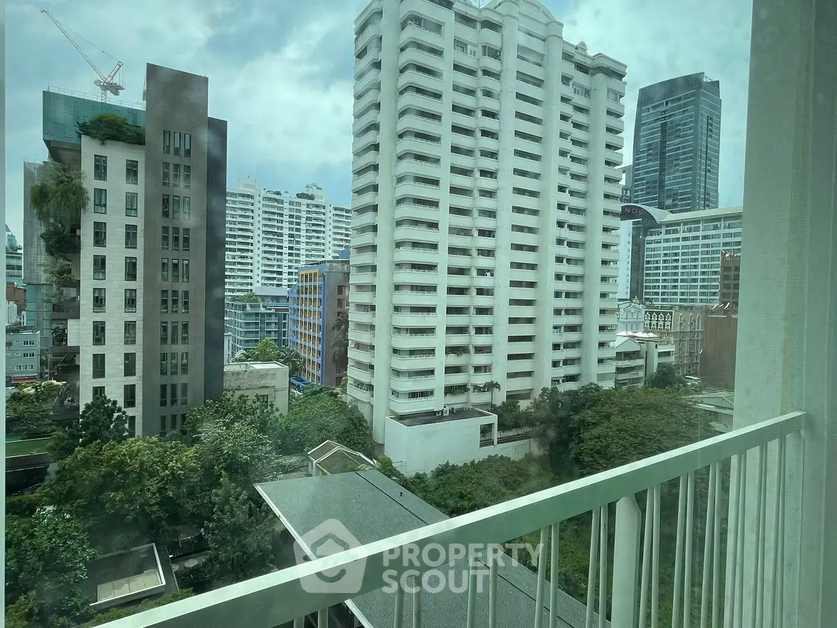 Stunning urban view from a high-rise balcony showcasing modern architecture and lush greenery.