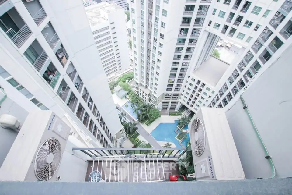Stunning high-rise view from balcony overlooking modern pool and urban landscape.