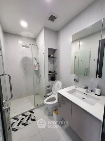 Modern bathroom with glass shower, sleek vanity, and elegant tile design.