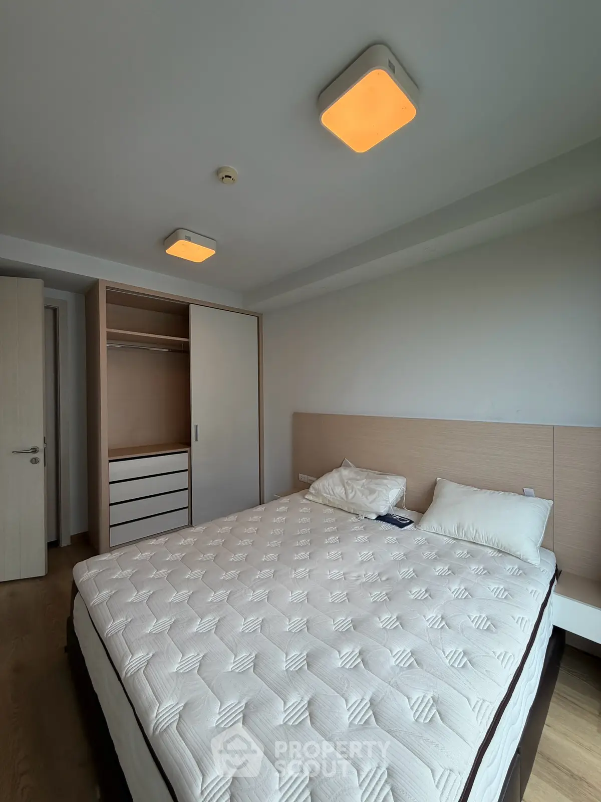Spacious bedroom with modern lighting and built-in wardrobe, perfect for comfortable living.