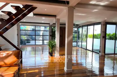 Spacious modern living room with wooden floors and large windows offering abundant natural light.