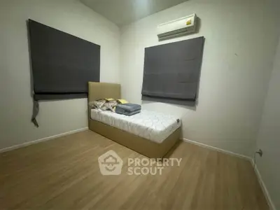 Cozy minimalist bedroom with single bed and air conditioning, perfect for a peaceful retreat.