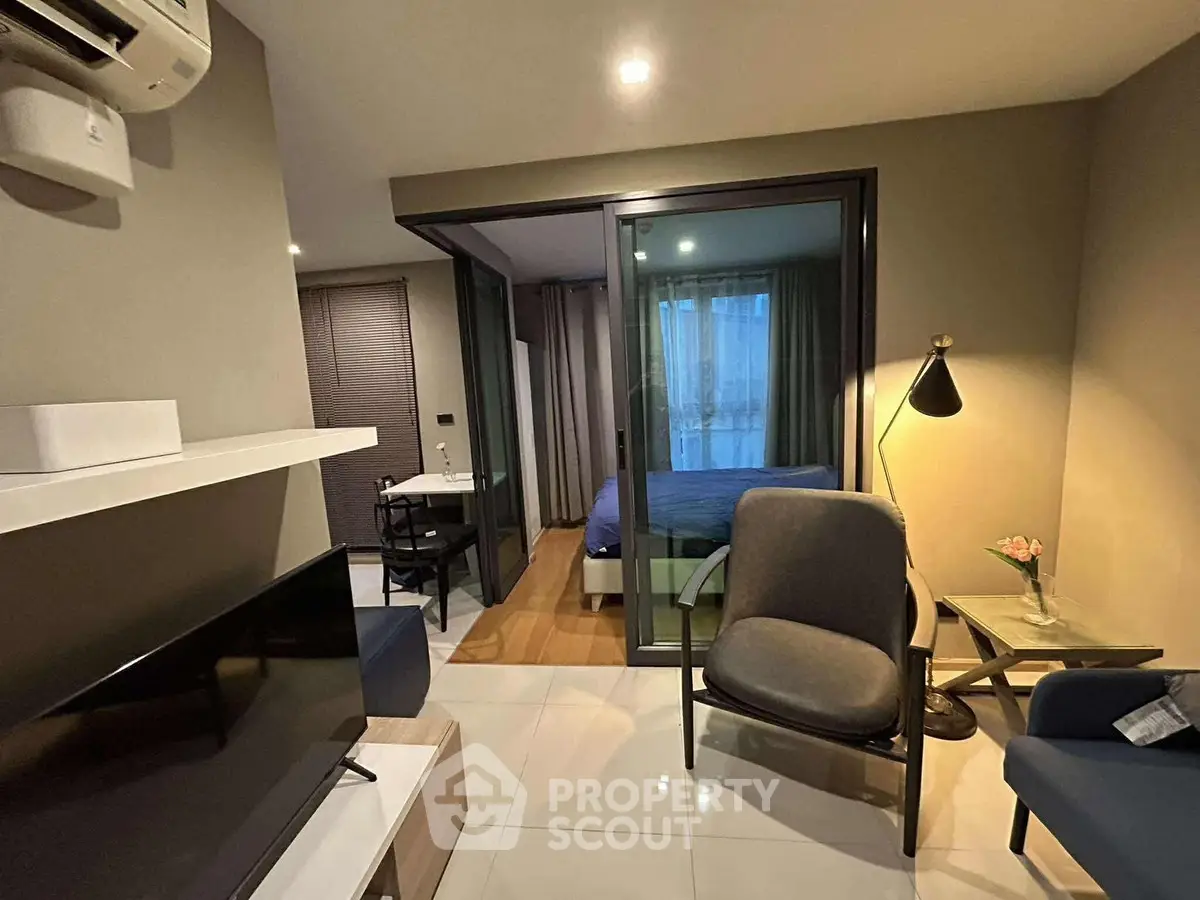 Modern apartment interior with cozy living area and glass partitioned bedroom