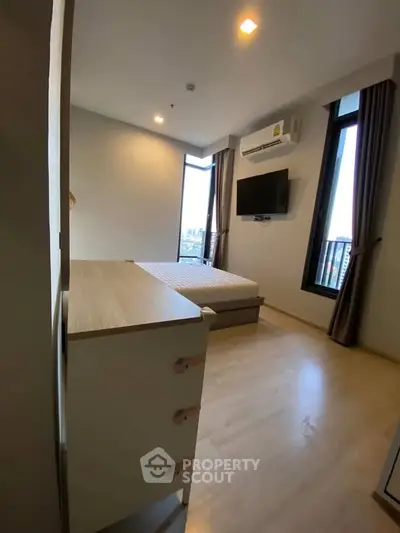 Modern bedroom with city view, featuring sleek furniture and natural light.