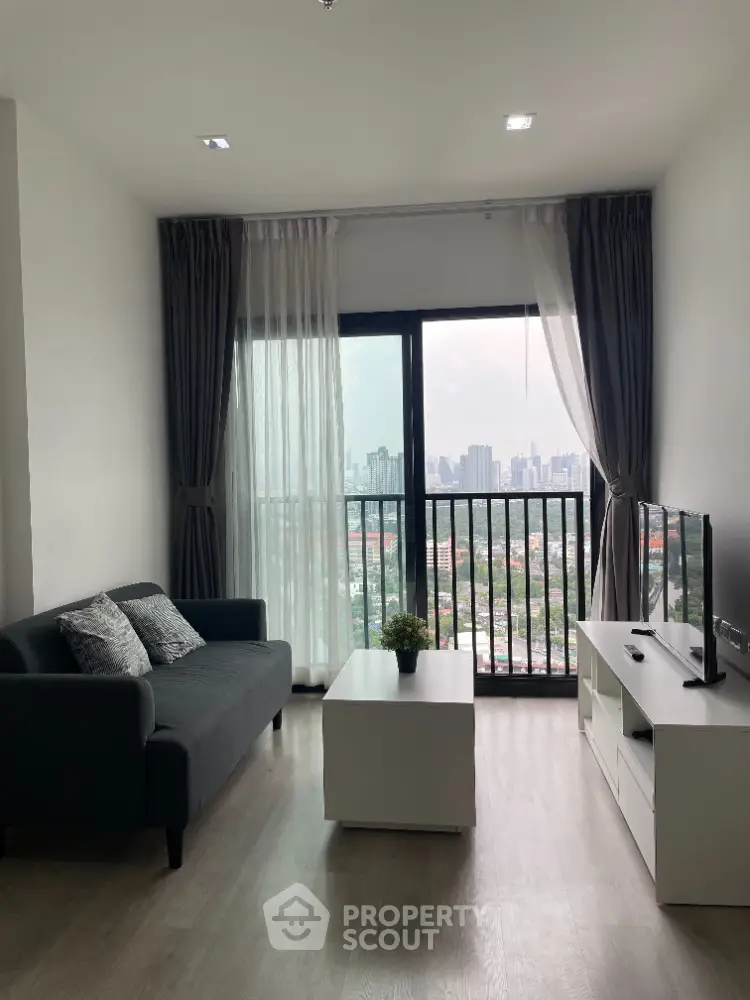 Modern living room with city view, stylish sofa, and sleek TV unit in high-rise apartment.