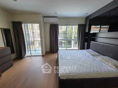 Spacious bedroom with large windows and balcony access in modern apartment