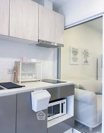 Modern compact kitchen with sleek cabinetry and built-in microwave, featuring a minimalist design and efficient layout.