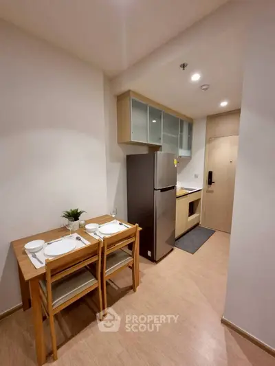 Modern compact kitchen with dining area and stainless steel fridge