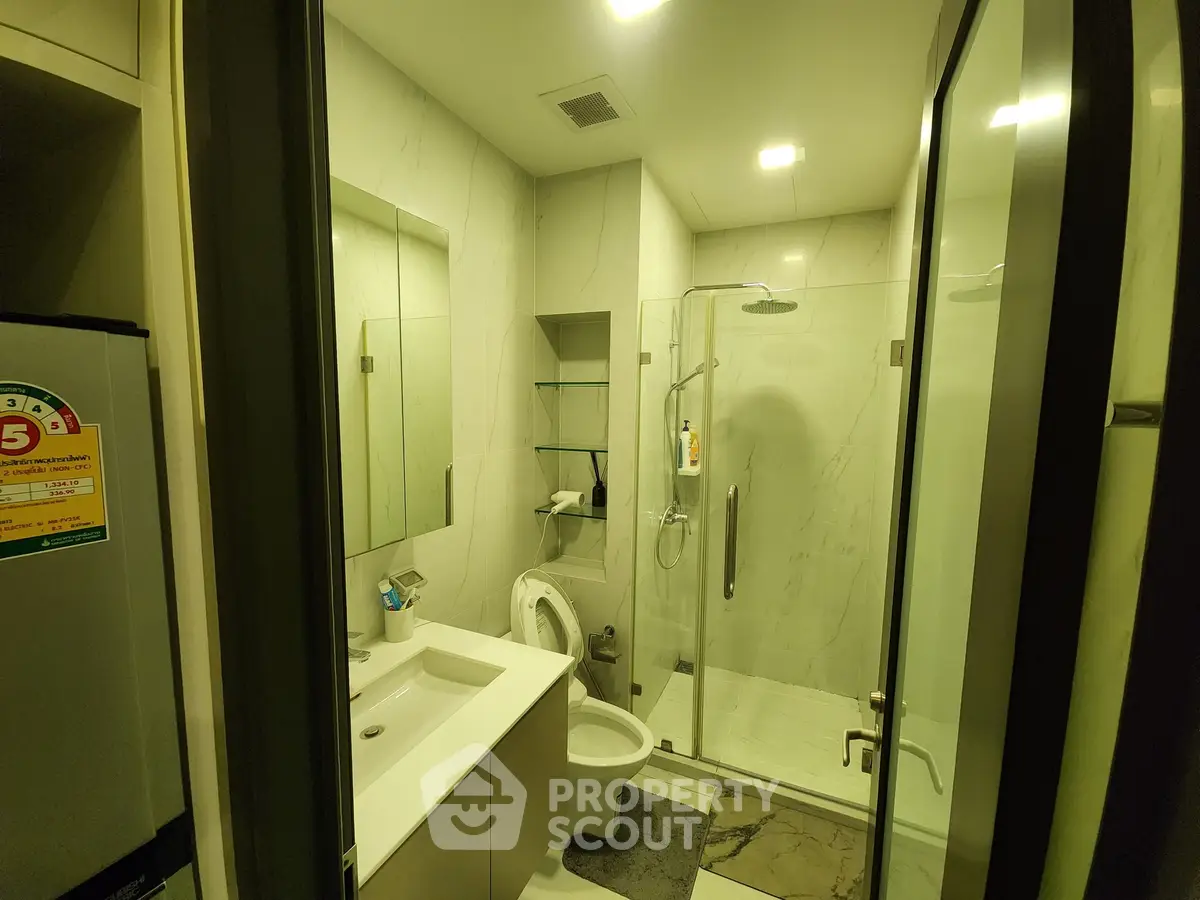 Modern bathroom with glass shower and sleek fixtures in luxury apartment.